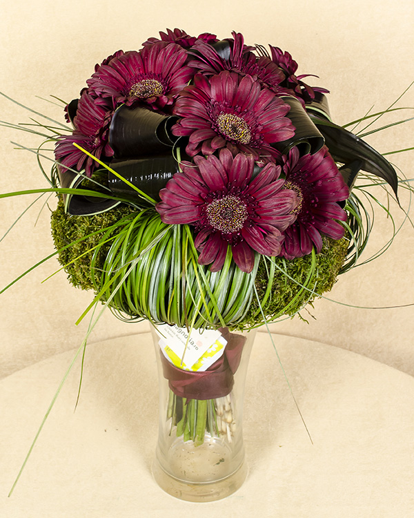 Dark brownish-red bouquet with gerbera and a moss wreath