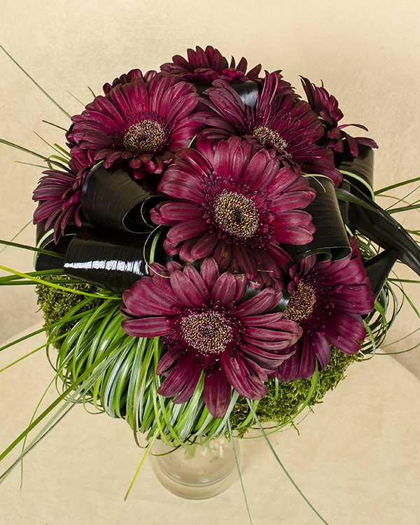 Dark brownish-red bouquet with gerbera and a moss wreath